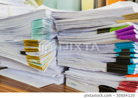 Pile of unfinished documents on office desk 30884120