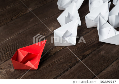 Business leadership concept with white and color paper boats on wooden table Business leadership concept with white and color paper boats on wooden table 30889547