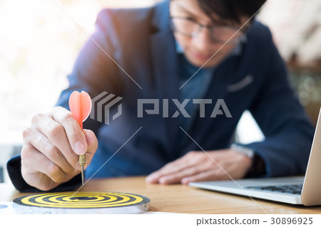 Business Man hand holding a target with darts hitting the center Business Man hand holding a target with darts hitting the center 30896925