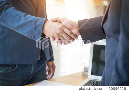 Two confident business man shaking hands during a meeting in the Two confident business man shaking hands during a meeting in the 30896926