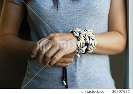 Cowrie shell bracelets on the wrist of woman 30897685
