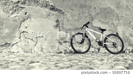 Bicycle near a stone wall 30897758