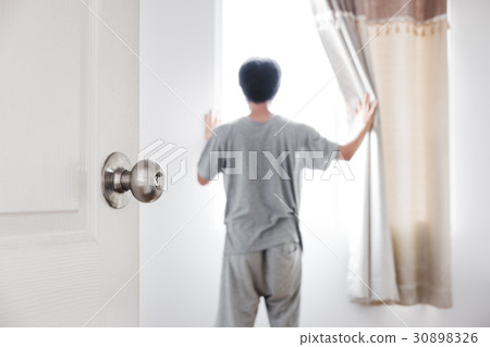 Door opened to the room, with a man open curtain  30898326