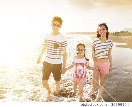 happy family walking on the beach at sunset happy family walking on the beach at sunset 30899304