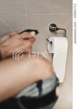 young man reading in the toilet 30901713