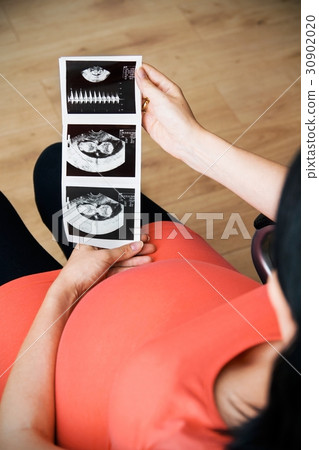 Pregnant woman looking at an ultrasound 30902020