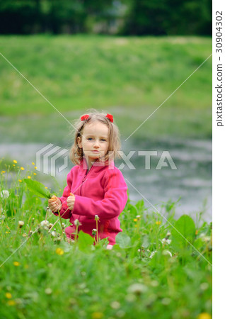 A small girl is sitting alone in the grass on the 30904302