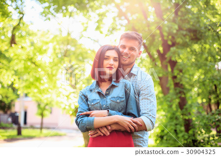 Happy young couple at park standing and laughing Happy young couple at park standing and laughing 30904325