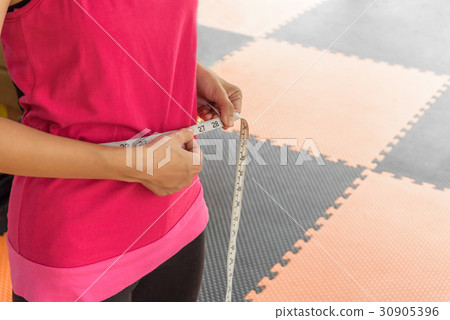 sport woman with measuring tape on a slender waist sport woman with measuring tape on a slender waist 30905396