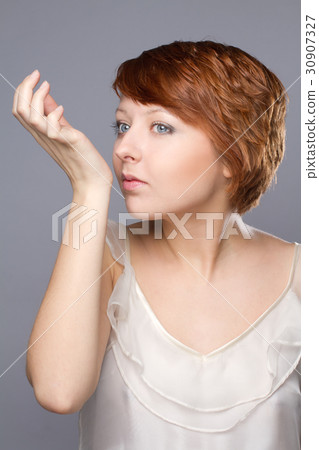 young woman smells pafrume on her hand 30907327