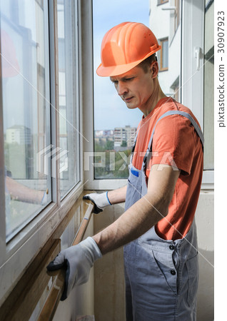 Worker is installing a window sill. 30907923
