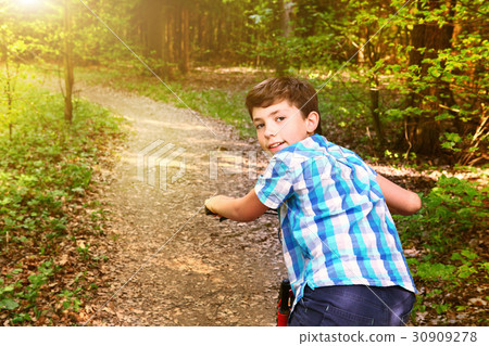 teen boy on bicycle ride through the summer forest 30909278