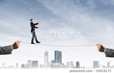 Business concept of risk support and assistance with man balancing on rope 30918275