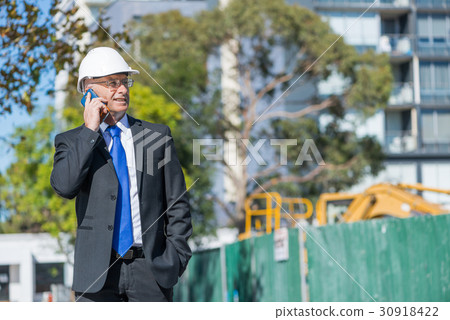 Man architector outdoor at construction area having mobile conversation 30918422