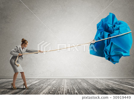 Woman pulling with effort big crumpled ball of paper as creativity sign 30919449
