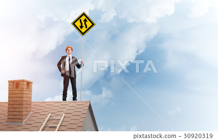 Engineer man on brick roof with sign in hands. Mixed media Engineer man on brick roof with sign in hands. Mixed media 30920319