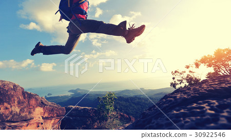 young woman hiker jumping on mountain peak 30922546