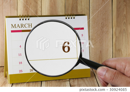 Magnifying glass in hand on calendar. Magnifying glass in hand on calendar. 30924085