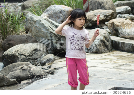 Little girl eating a sausage 30924656