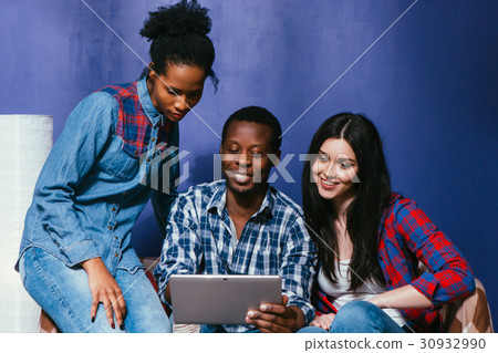 Three friends with tablet watch photos on couch Three friends with tablet watch photos on couch 30932990