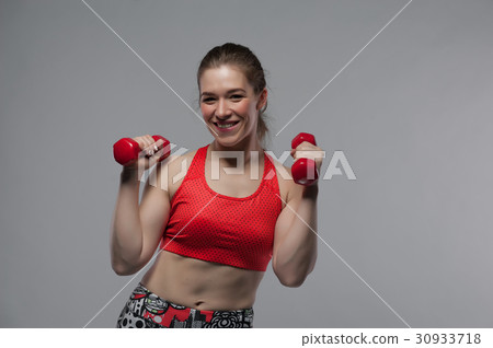 Smiling fitness woman posing with red dumbbells 30933718