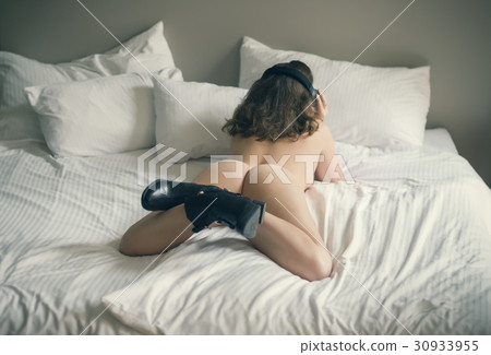 Beautiful naked girl lies on a bed in headphones 30933955