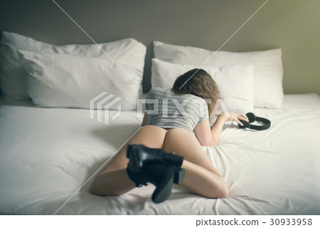 Beautiful naked girl lies on a bed in headphones 30933958
