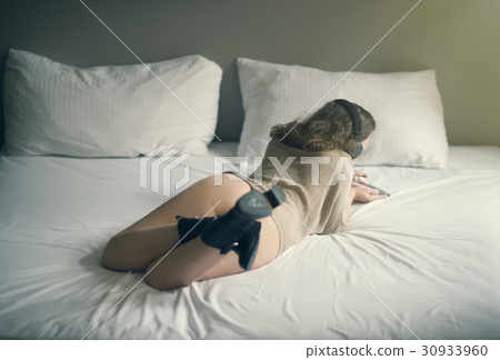 Beautiful naked girl lies on a bed in headphones 30933960