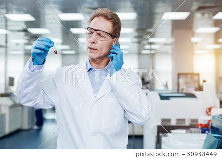 Serious practitioner holding phone near left ear 30938449