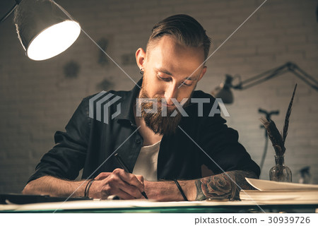 Happy bearded male creating pictures at table 30939726