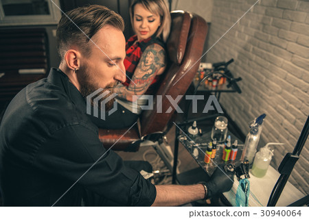 Calm male master putting color in tattoo machine 30940064