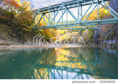 River of autumnal leaves and blue iron bridge 30940068