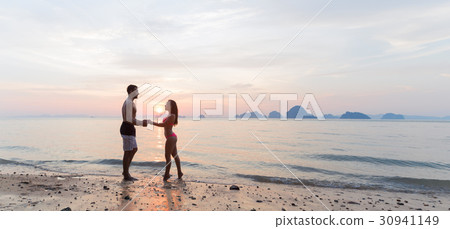 Couple Holding Hands On Beach At Sunset, Young Couple Holding Hands On Beach At Sunset, Young 30941149