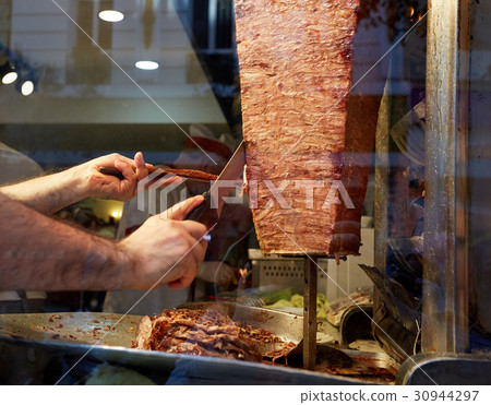 An arm moving to cut the kebab meat 30944297