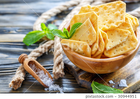Crackers with salt in a wooden bowl. Crackers with salt in a wooden bowl. 30944951