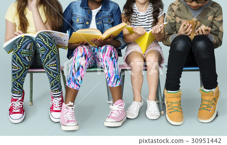 Diverse group of kids sitting in a row reading books 30951442