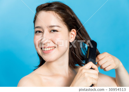 A woman using a hair iron A woman using a hair iron 30954513