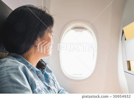Asian Woman sitting at window seat in airplane 30954932