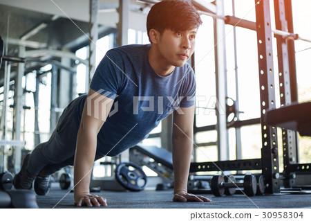 Young Asian man exercising in the fitness gym Young Asian man exercising in the fitness gym 30958304