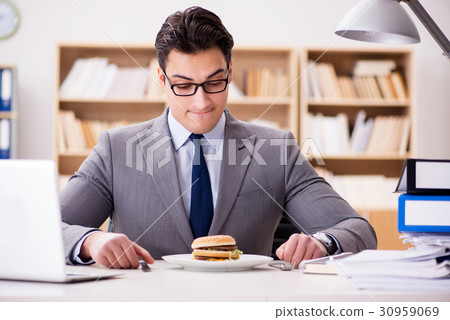 Hungry funny businessman eating junk food sandwich 30959069