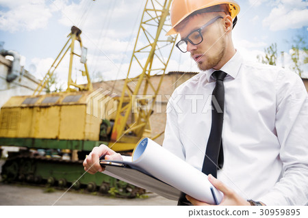 Engineer builder in a helmet holds drawings at Engineer builder in a helmet holds drawings at 30959895