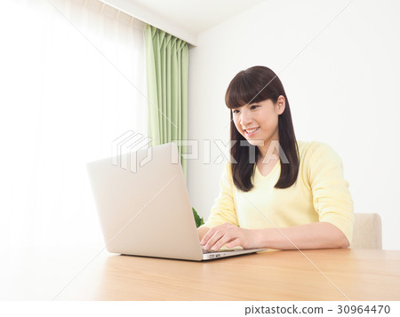 A woman looking at the screen of a computer with a smile A woman looking at the screen of a computer with a smile 30964470
