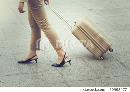 woman walking carrying a suitcase woman walking carrying a suitcase 30968477