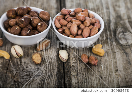 Nuts in a plate on a  wooden table. 30968478