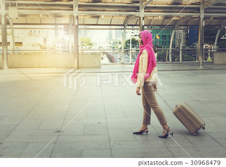 Arab woman walking carrying a suitcase Arab woman walking carrying a suitcase 30968479