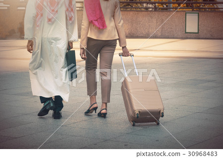 Arab man and woman walking carrying a suitcase Arab man and woman walking carrying a suitcase 30968483