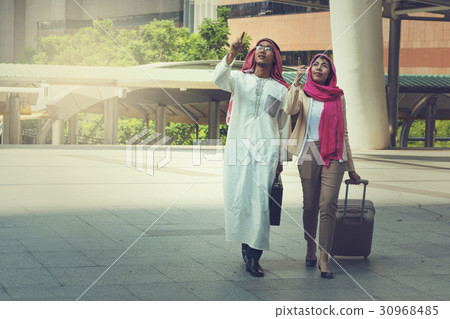 Arab man and woman walking carrying a suitcase Arab man and woman walking carrying a suitcase 30968485