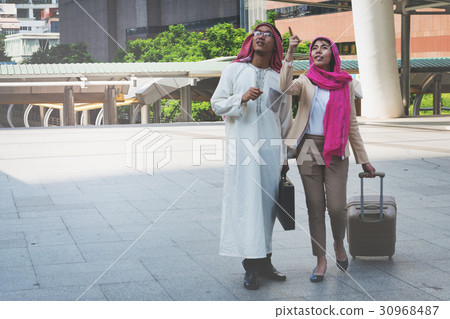 Arab man and woman walking carrying a suitcase Arab man and woman walking carrying a suitcase 30968487
