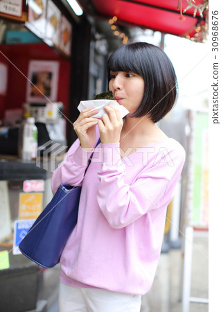 A young woman eating fast food 30968676