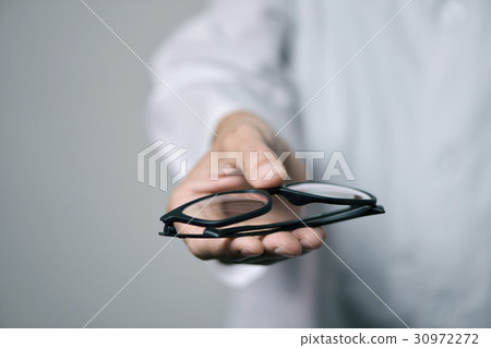 optician man bringing a pair of eyeglasses optician man bringing a pair of eyeglasses 30972272